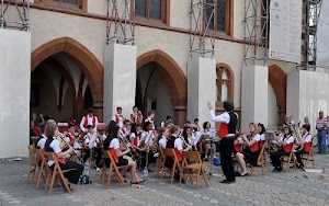 archi, musicisti, strumenti, orchestra, seduti, sedie, rosso, banda, nero, direttore, musica, persone, piazza, bianco, divisa, divise, finestre, maestro